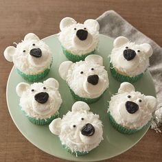 some cupcakes with white frosting and black noses are on a green plate