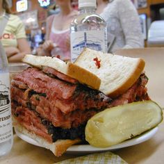 a sandwich and pickle on a plate next to a bottle of water at a restaurant