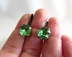 These are wonderful earrings! They are small and subtle, in a unique and flattering color, but with enough sparkle to catch the eye! Stone Size: 10mm / .4 inches / 1 cm Total Length: 18mm long / 1 inch / 1.8 cm Stone Details: vintage Czech glass Peridot green crystals. Setting: Cast brass lever-back setting. You choice of Gold, Antique Gold (shown) or Silver plating. These are bright and lively earrings made with high-quality vintage glass Rhinestones. A really eye-catching and versatile pair of Green Crystal Earrings For Wedding, Green Round Crystal Earrings For Wedding, Green Crystal Wedding Earrings With Ear Wire, Bridesmaid Green, Bridal Earring, Georgian Jewelry, Wedding Green, Peridot Crystal, Peridot Green