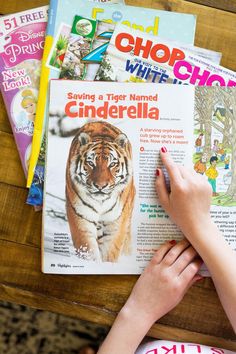 a person is reading a magazine with a tiger on the front cover and other children's books behind them