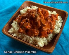 a wooden bowl filled with rice covered in meat and gravy on top of a blue cloth