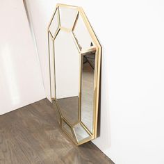 a mirror sitting on top of a wooden floor next to a white wall in a room