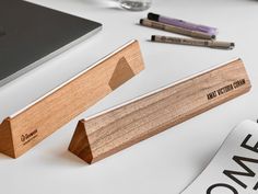 two wooden business card holders sitting on top of a desk next to a laptop computer