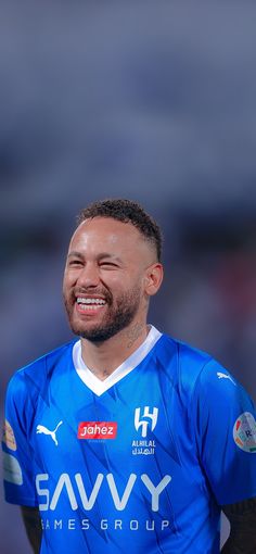 a man in a blue soccer uniform smiles at the camera