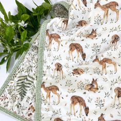 the blanket has deers on it and is next to some plants with green leaves