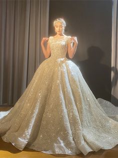 a woman in a wedding dress standing on a stage with her hands behind her back