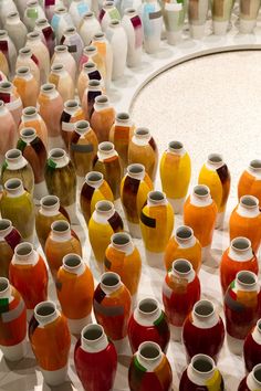 many different colored vases are arranged on a white surface with circles in the background