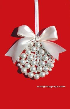 a christmas ornament with white pearls and a bow on it's side