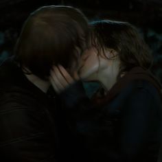 two people are kissing in the dark with their faces close to each other and one person is holding his head