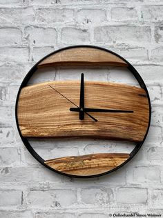 a clock made out of wood and metal on a white brick wall with black hands