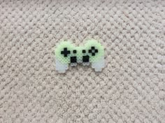 two green and black pixelated sheeps on a white carpet with one earring in the shape of a cross