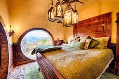 a bed room with a neatly made bed next to an arched window and a wooden headboard