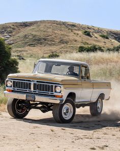 an old pick up truck driving down a dirt road