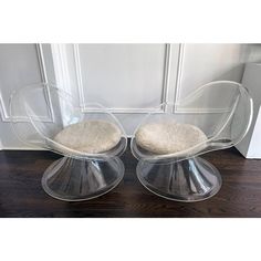 two clear acrylic chairs sitting on top of a wooden floor next to a white door