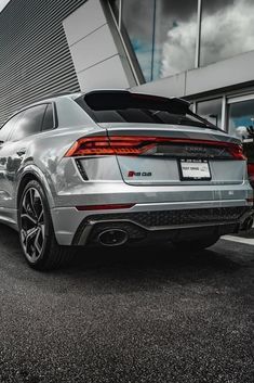 the rear end of a silver car parked in front of a building