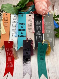 colorful bookmarks with sayings on them sitting next to flowers and bookshelves