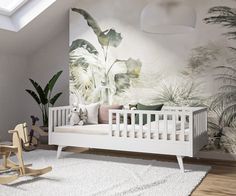 a baby's room with a white crib, rocking chair and wall mural