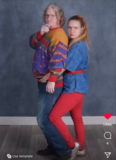 two people standing in front of a gray wall