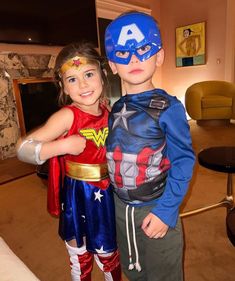 two young children dressed up as superheros posing for a photo in the living room