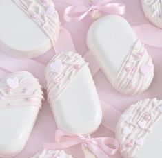 some white cookies with pink bows and hearts on them are laying next to each other