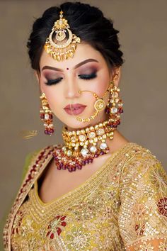 a woman with makeup and jewelry on her face, wearing an elaborate gold necklace and earrings