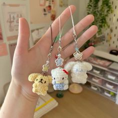 someone is holding three small stuffed animals in their hand, and they are wearing tiny charms