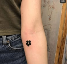 a small black flower tattoo on the arm