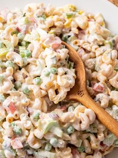 a white bowl filled with macaroni salad and a wooden spoon