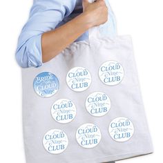 a person holding a tote bag with nine badges on it that say cloud nine club