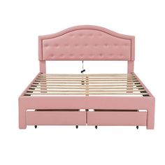 a pink bed frame with two drawers underneath the headboard and foot board, in front of a white background