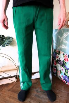 Beautiful Vintage track pants from the late 1980s. Nice green color with white stripes on the sides. Comfortable cotton blend fabric. Regular fit. One zipped side pocket, zipped leg openings. Elasticated waistband, tie band in the waist to adjust the fit. Unisex. For an amazing true vintage street style wear with a simple tee and sneakers! BRAND: Grasshoppers ERA: 1980s COLOUR: Green, white FABRIC: 45% nylon, 37% cotton, 18% viscose SIZE: Vintage size 7, fits best men's size L-XL, can also be wo Green Sweatpants With Side Stripes For Streetwear, Green Bottoms With Side Stripes For Streetwear, Green Streetwear Pants With Side Stripes, Green Side Stripe Pants For Streetwear, Green Pants With Side Stripes For Streetwear, Casual Green Bottoms With Three Stripes, Green Sporty Pants With Side Pockets, Sporty Green Pants With Side Pockets, Green Athleisure Bottoms With Side Stripes