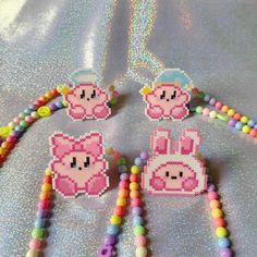 some beads are laying next to each other on a table with pink and yellow decorations