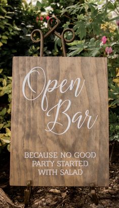 an open bar sign in front of some bushes