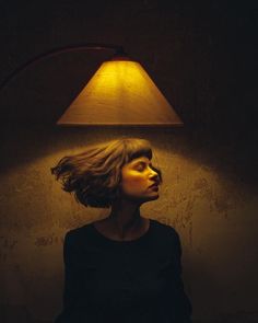 a woman standing in front of a lamp with her head turned to look like she's floating