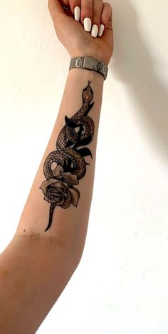 a woman's arm with a snake tattoo on it, and a rose in the middle