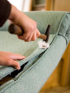 someone using a pair of scissors to clean the back of a green chair with fabric