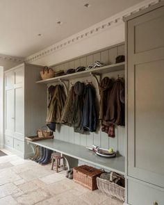 a coat rack filled with lots of coats and shoes next to a bench in a room