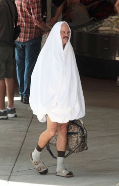 a man in a white robe walking down the street with a bag on his back