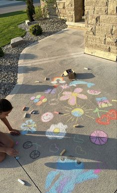 a child is drawing on the sidewalk with chalk