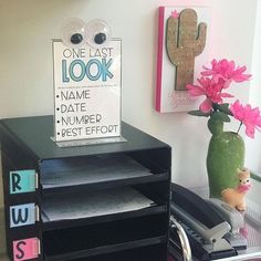 a black desk with pink flowers in a green vase and a sign that says one last look name date numpep best effort