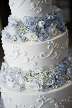 a three tiered wedding cake with blue and white flowers