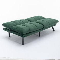 a green futon couch sitting on top of a white floor next to a wall