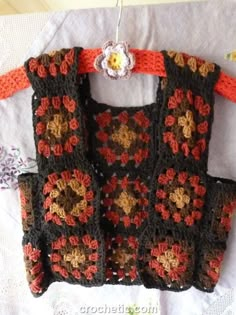 a crocheted purse is hanging on a white tablecloth with flowers in it