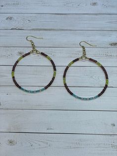 Pair of seed bead hoop earrings measure about 2 inches round.  I used translucent brown & green seed beads around the hoop. At the bottom of the hoop there are 5 turquoise tube beads with clear seed beads in between.  The beaded earrings are attached to gold earring wires.  These fun statement earrings will compliment any outfit perfectly.  Great for any season. Seed Bead Hoop Earrings, Bead Hoop Earrings, Earring Wires, Beaded Hoop Earrings, Beaded Hoops, Gold Earring, Seed Bead Earrings, Tube Beads, Bead Earrings