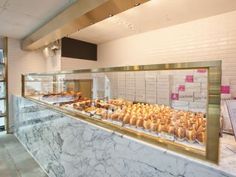 a display case filled with lots of pastries on top of a marble counter next to a window