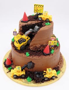 a three tiered chocolate cake with construction vehicles on top