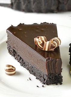 a piece of chocolate cake on a white plate next to two small pieces of pie