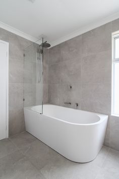 a large white bath tub sitting in a bathroom next to a window with no curtains