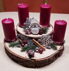 three candles sitting on top of a tree slice with pine cones and other christmas decorations