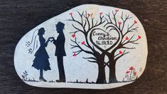 a painted rock with a silhouette of a man and woman holding hands under a tree